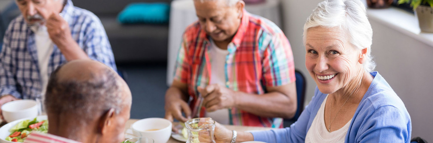 A group of elderly people sitting at a table eating food